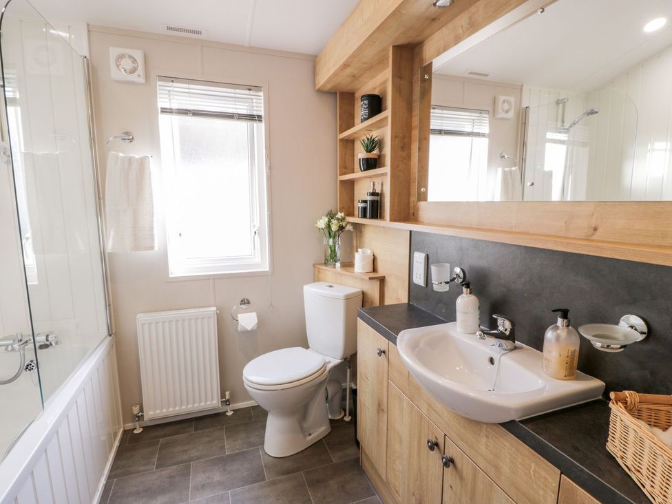 A bathroom with a bathtub, toilet, and sink at Serenity Lodge in Wemyss Bay