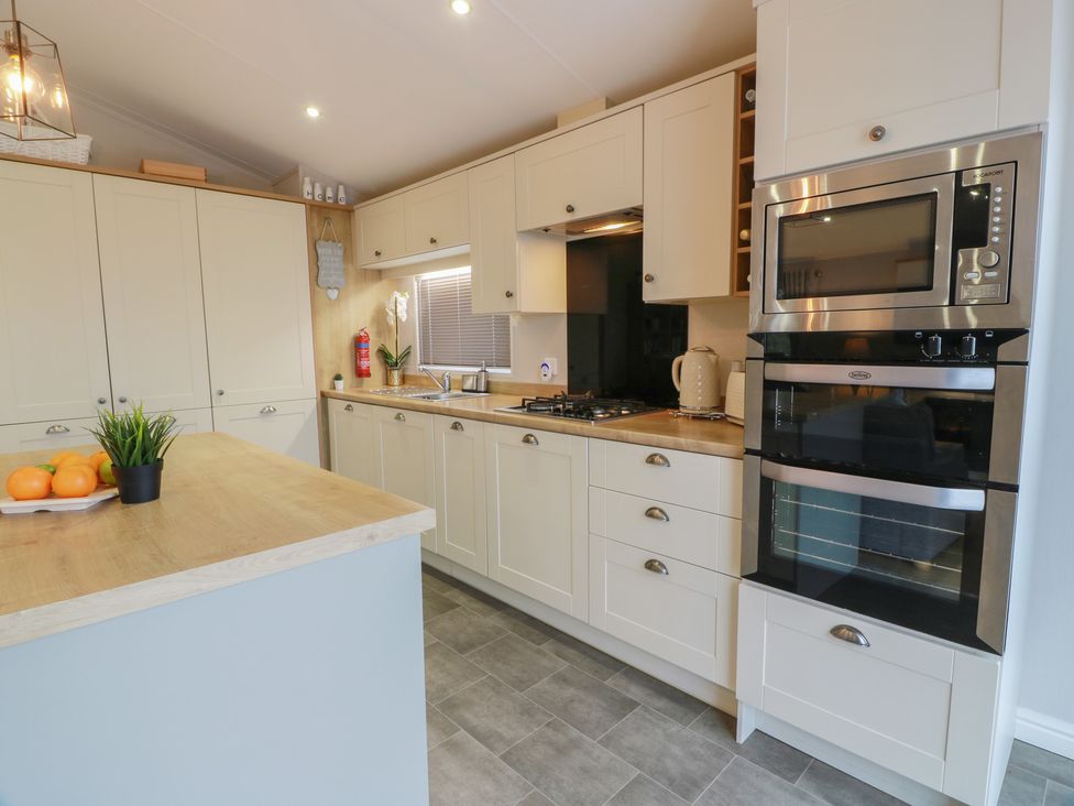 A kitchen with cabinets and appliances at Serenity Lodge in Wemyss Bay
