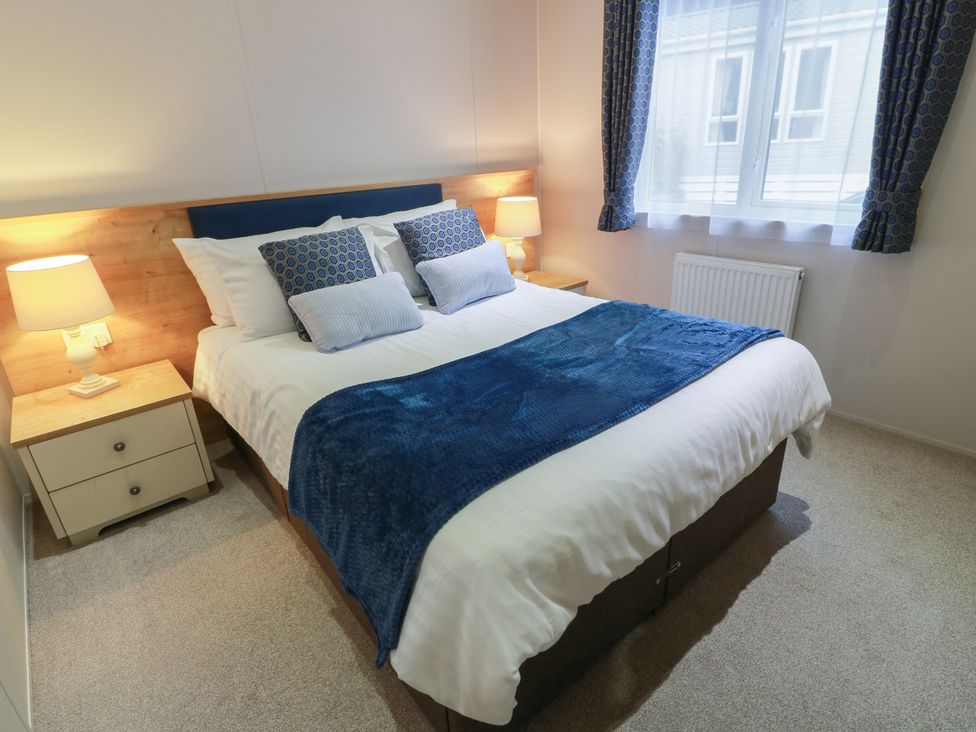 A bedroom with a bed and bedside tables at Serenity Lodge in Wemyss Bay