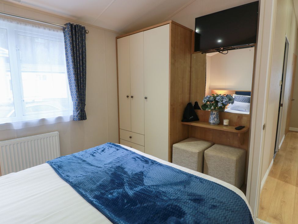A bedroom with a bed, television and wardrobe at Serenity Lodge in Wemyss Bay