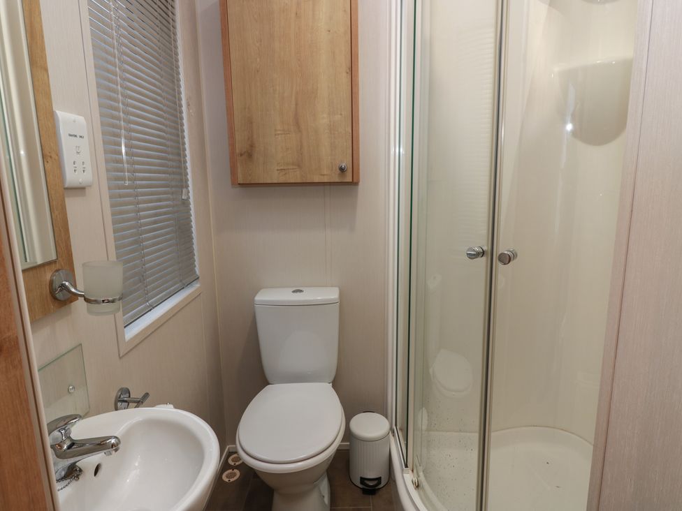 A bathroom with a toilet, sink and shower at Serenity Lodge in Wemyss Bay