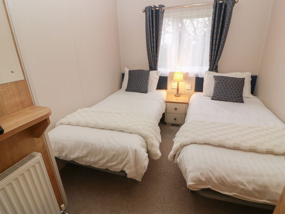 A bedroom with two beds and a lamp at Serenity Lodge in Wemyss Bay