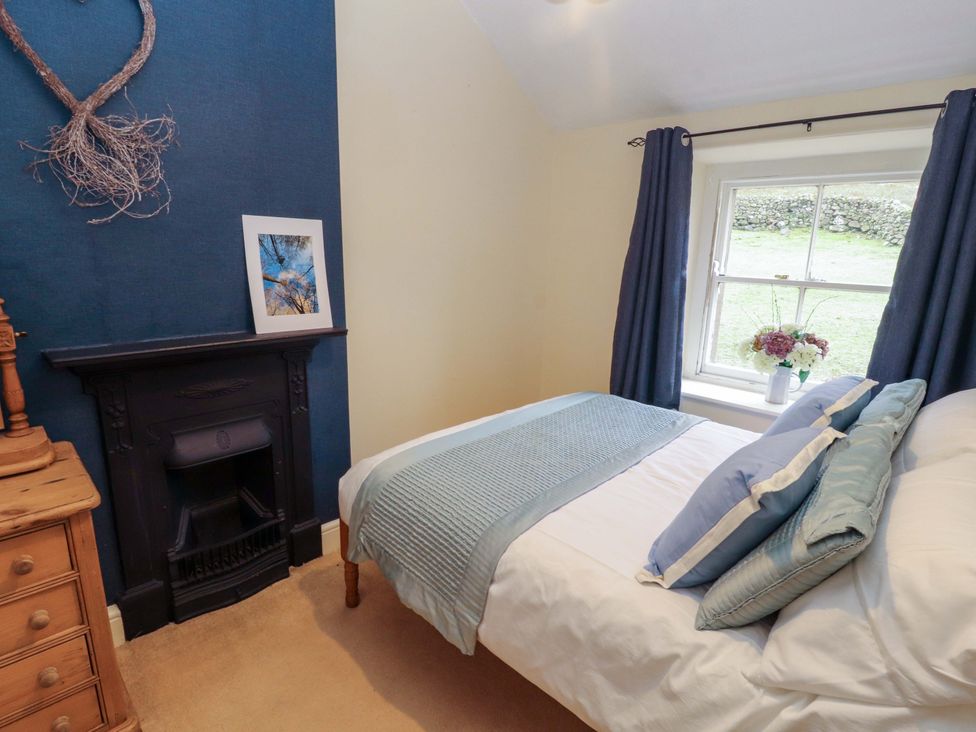 A bedroom with a bed and fireplace at Easthwaite Cottage in Holmrook near Easthwaite Farm