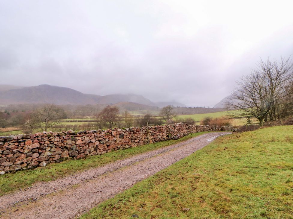 A dirt road beside a stone wall with mountains in the background at Easthwaite Cottage in Holmrook near Easthwaite Farm