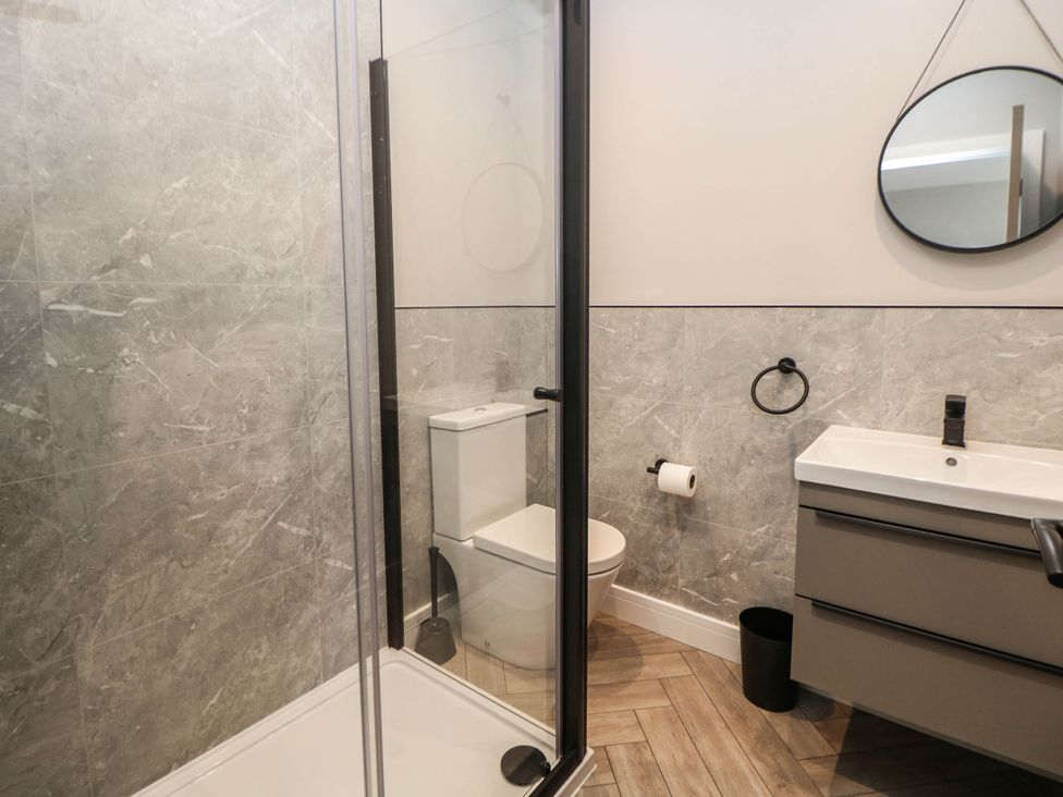 A bathroom with a shower, toilet, sink, and mirror at The Bungalow in Matlock