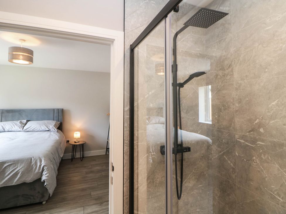 A shower view into a bedroom with a bed and bedside table at The Bungalow in Matlock