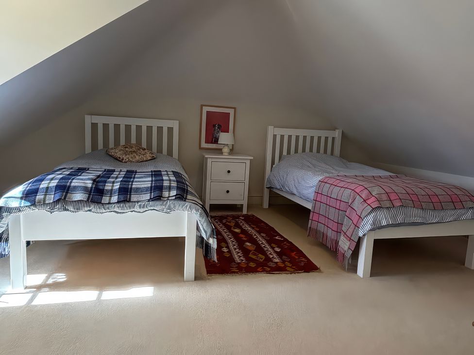 A bedroom with two beds and a nightstand at New Barn in Broad Chalke
