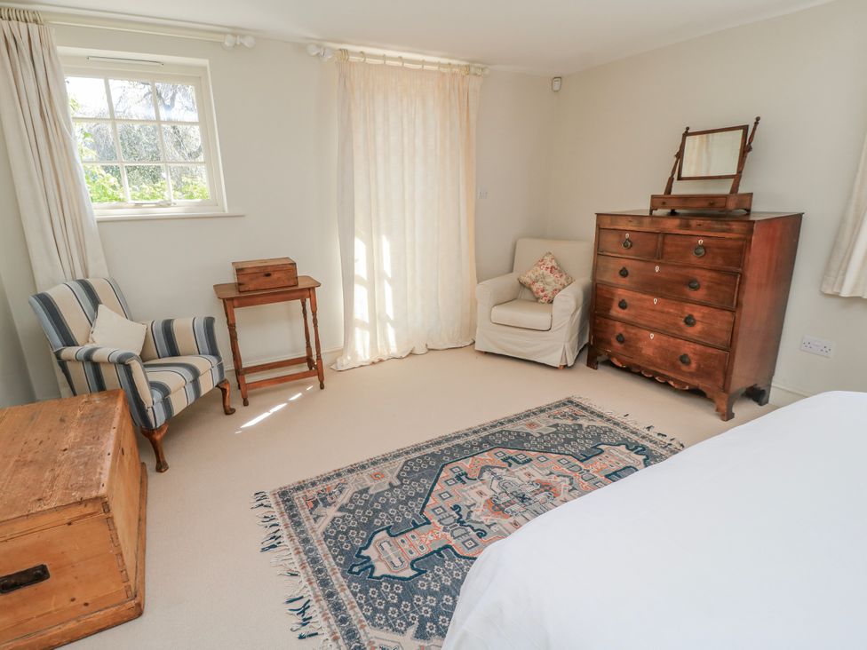 A bedroom with a chair, a table, and a dresser at New Barn in Broad Chalke
