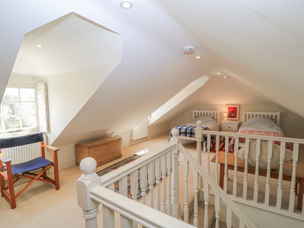 A bedroom with two beds and an armchair at New Barn in Broad Chalke