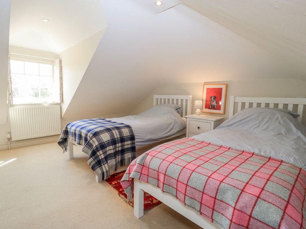 A bedroom with two beds and a window at New Barn in Broad Chalke