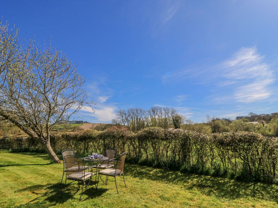A garden with a table and chairs under a tree at New Barn in Broad Chalke