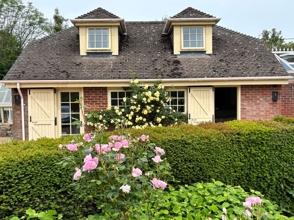 A garden view of a brick building with flowers at New Barn in Broad Chalke