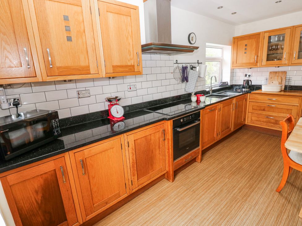 A kitchen with wooden cabinets and appliances at The Cwtch in Haverfordwest