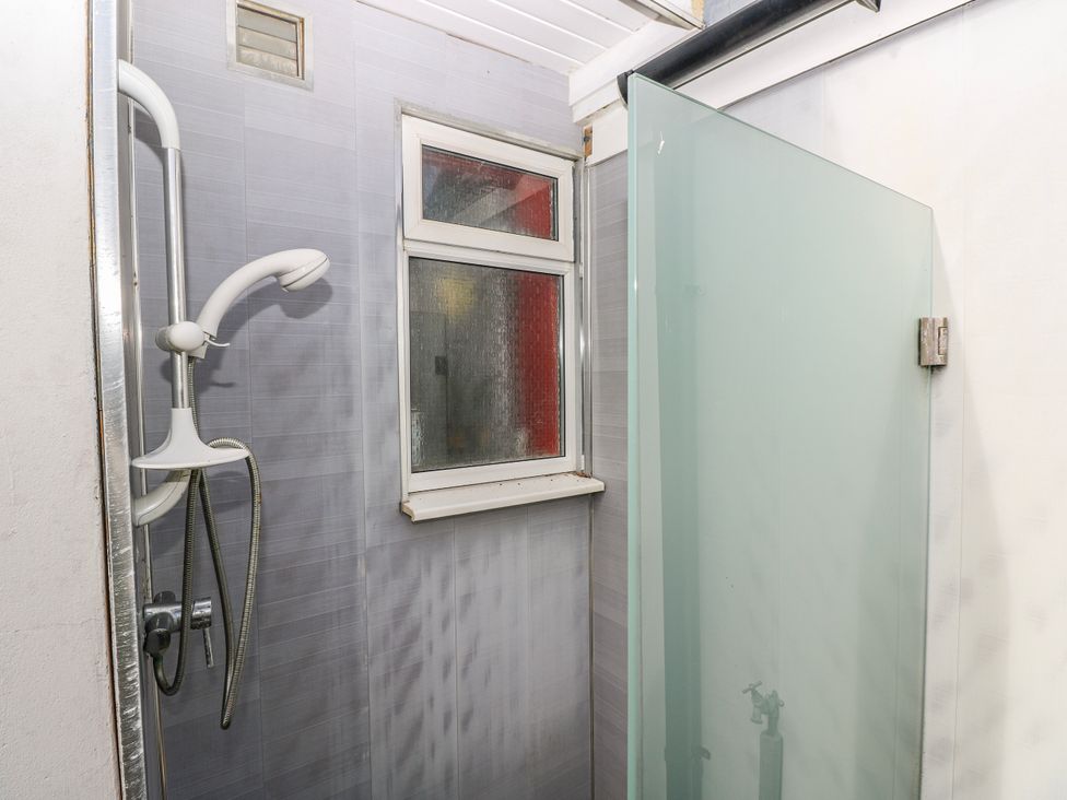 A shower with a glass panel and window in a bathroom at The Cwtch in Haverfordwest