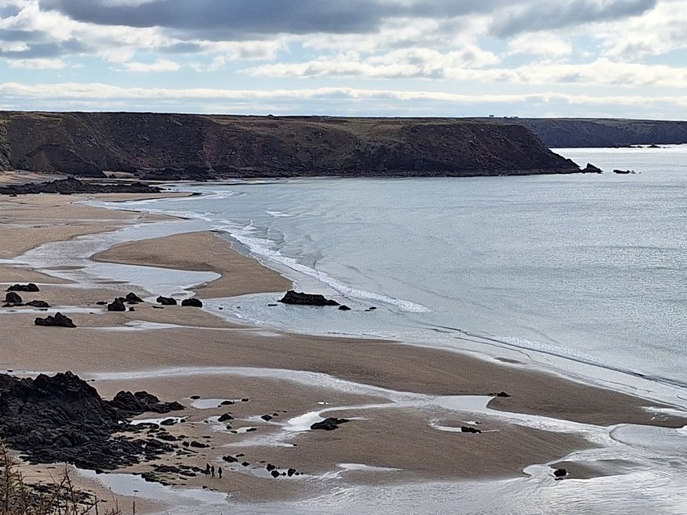 A beach with rocks and cliffs at The Cwtch in Marloes
