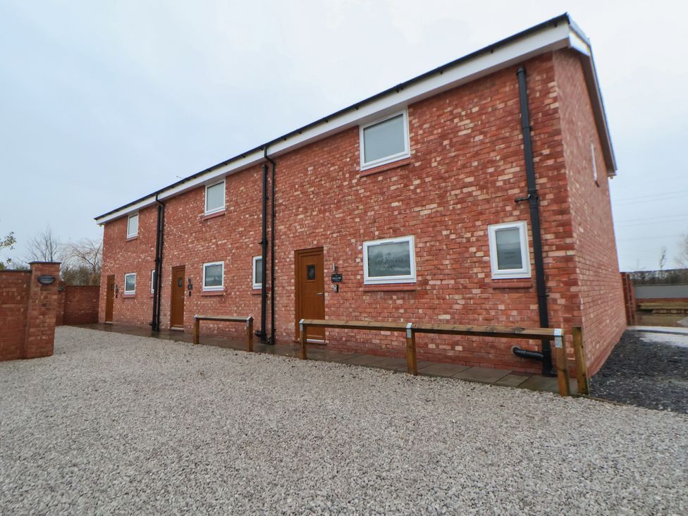 A brick house with windows and a gravel driveway at Ash Barn Chester