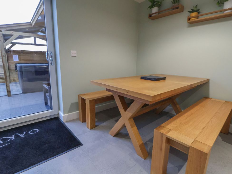 A dining area with a table and benches at Ash Barn in Saughall