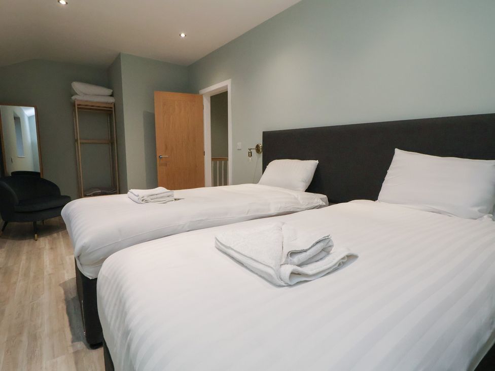 A bedroom with two beds and a chair at Oak Barn in Chester