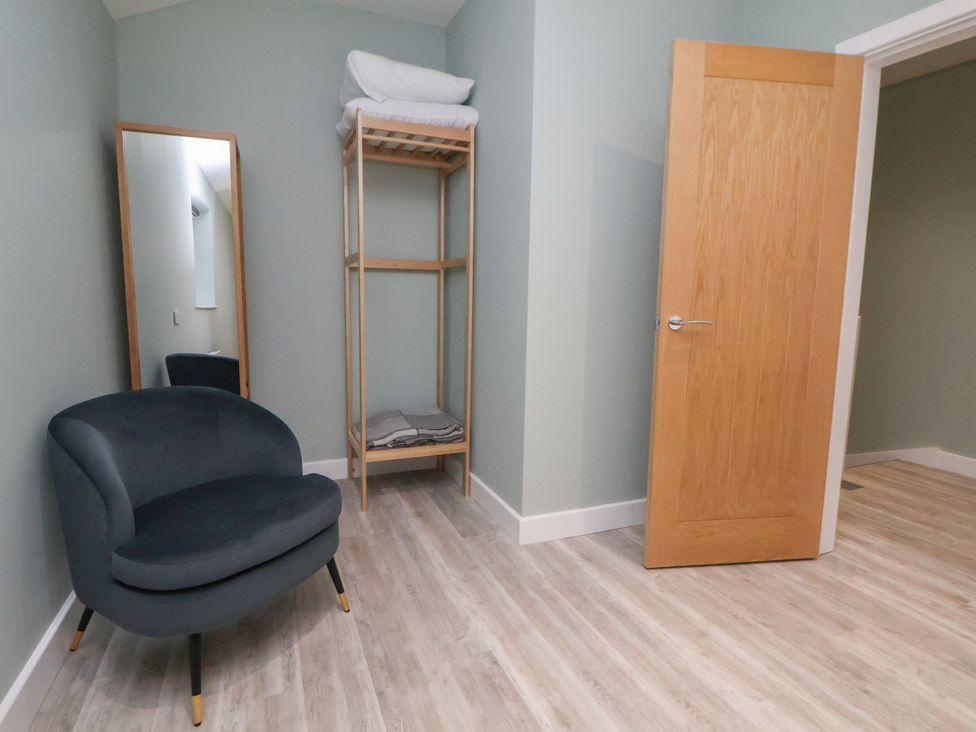 A room with a chair, mirror, shelf and door at Oak Barn in Chester