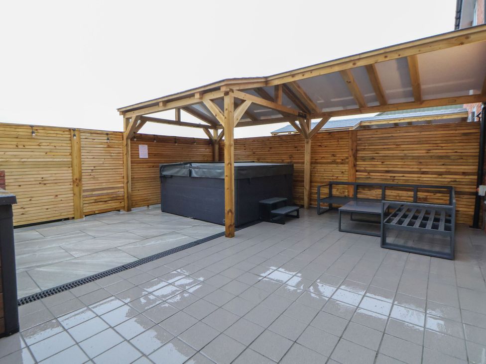 An outdoor area with a spa and seating at Oak Barn in Saughall