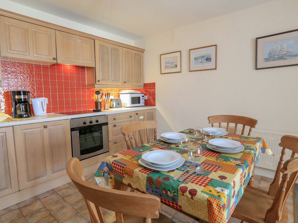 A kitchen with cabinets, countertop, appliances, and dining table at 3 The Salcombe, Salcombe