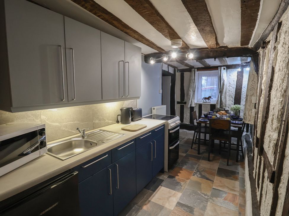 A kitchen with cabinets and dining table at Driftway Cottage in Diss