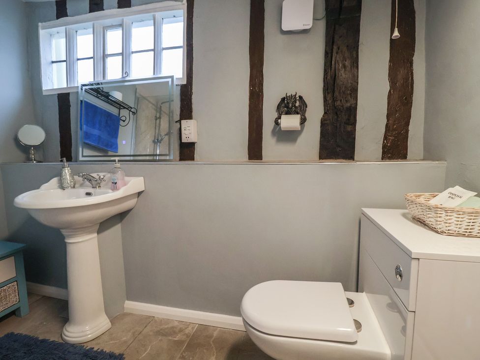 A bathroom featuring a sink, toilet, and mirror at Driftway Cottage in Diss