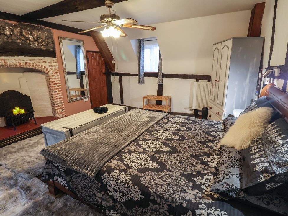 A bedroom with a bed and fireplace at Driftway Cottage in Diss