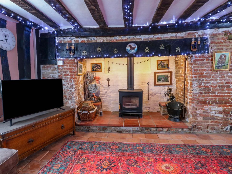 A living room with a wood stove and television at Driftway Stables Retreat Diss