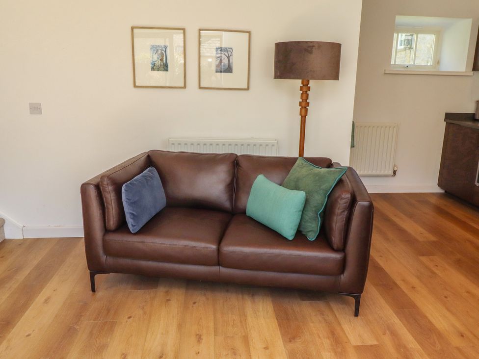 A sofa with cushions and a lamp in a living room at Snowdrop Cottage near Warkworth