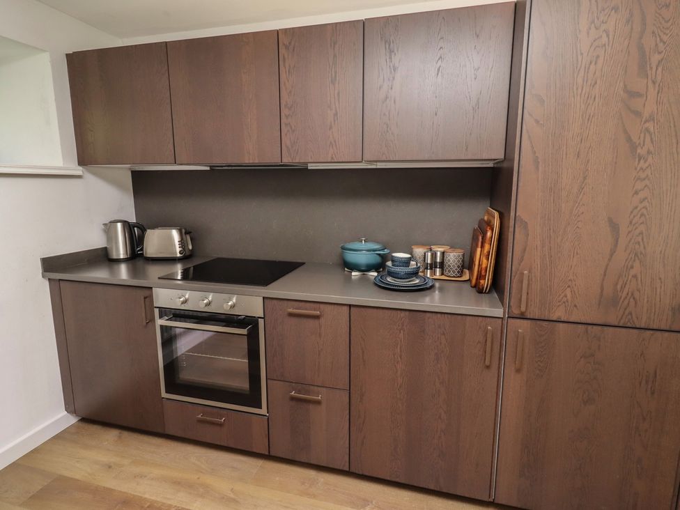 A kitchen with cabinets, stove, and utensils at Snowdrop Cottage near Warkworth