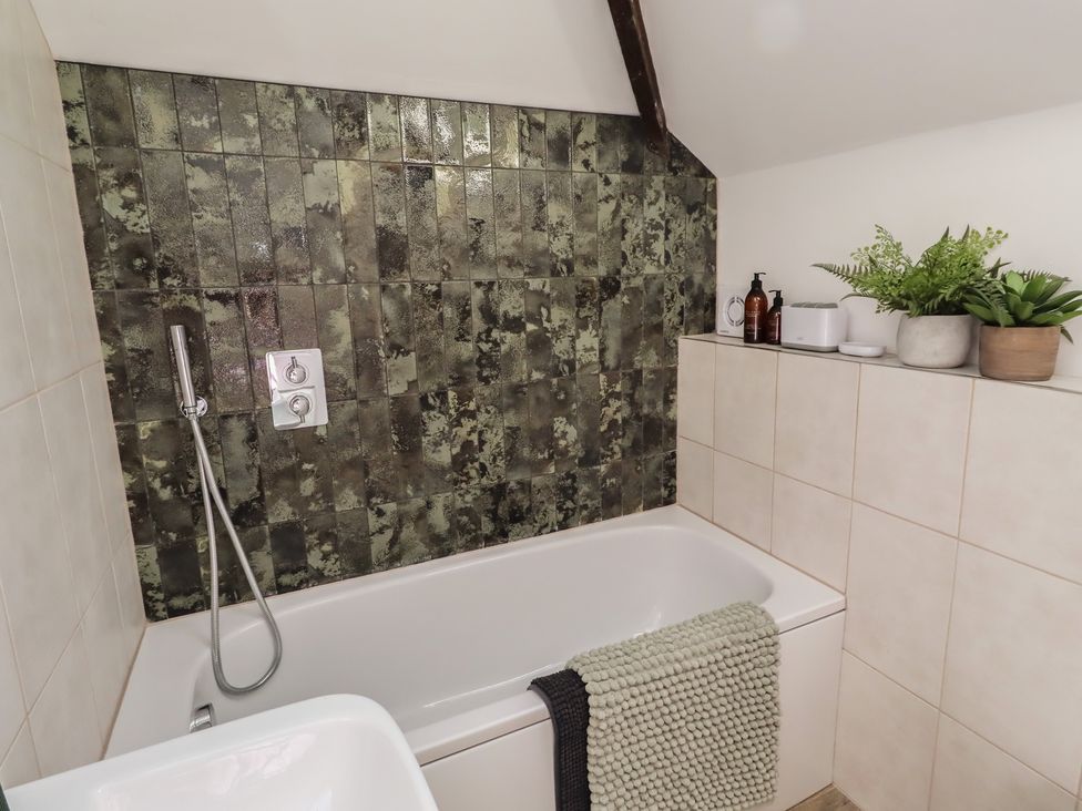 A bathroom with a bathtub and shower head at Snowdrop Cottage near Warkworth