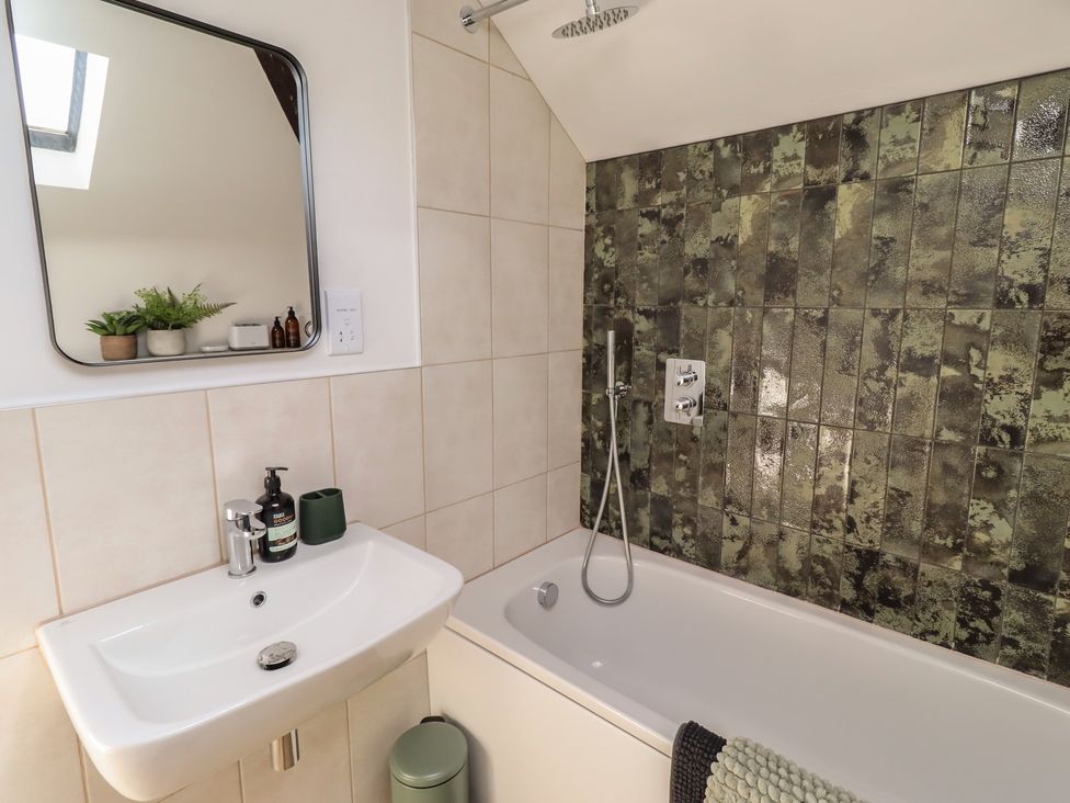 A bathroom with a bath and sink at Snowdrop Cottage near Warkworth