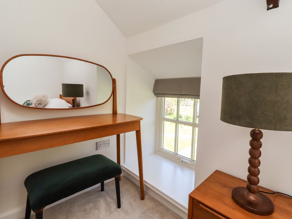A bedroom with a mirror, table and lamp at Snowdrop Cottage near Warkworth