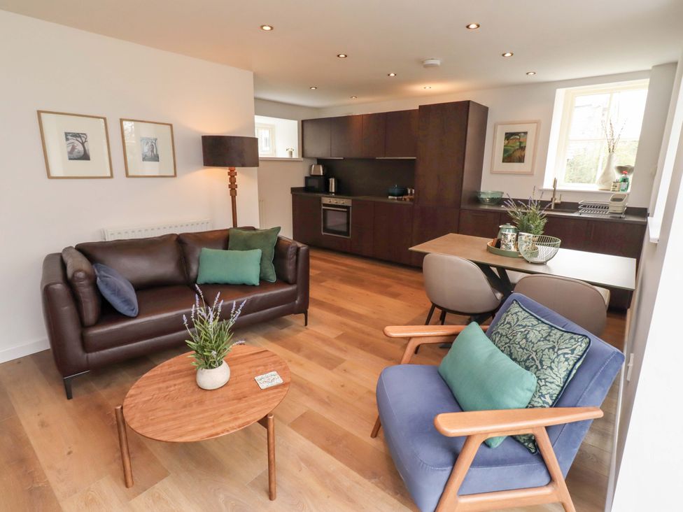 A living room with a sofa, table, and kitchen unit at Snowdrop Cottage near Warkworth