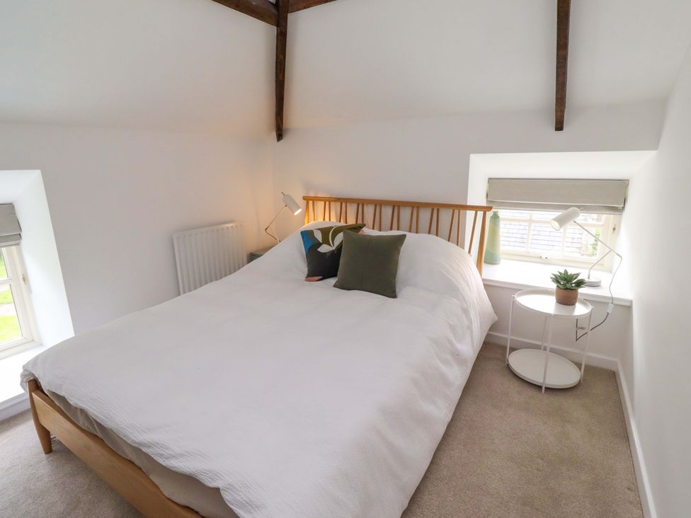 A bedroom with a bed and side table at Snowdrop Cottage near Warkworth
