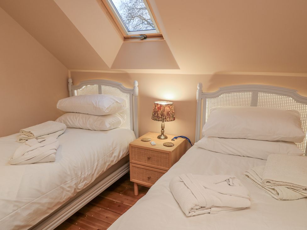 A bedroom with two beds and a lamp on a bedside table at Golden Valley View in Stroud