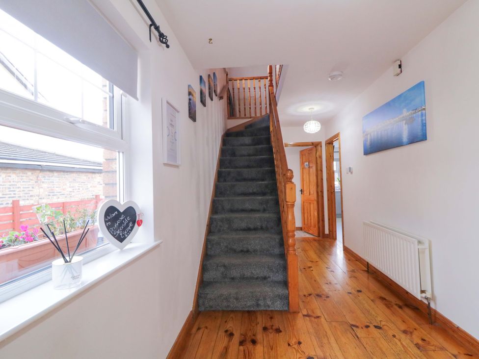 A hallway with a staircase and door at Primrose Seaside Escape