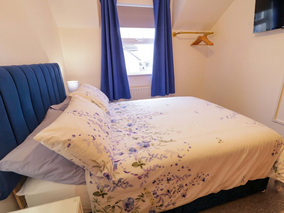 A bedroom with a bed and bedside lamp at Primrose Seaside Escape