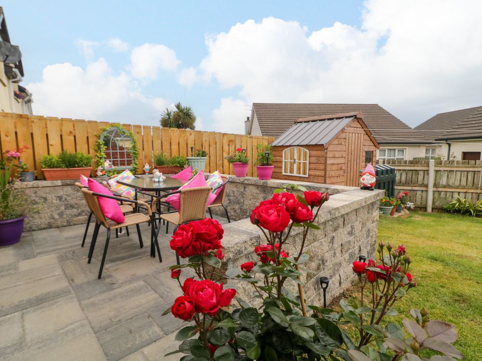 A garden with a table and chairs and flowers at Primrose Seaside Escape in Portrush, County Antrim