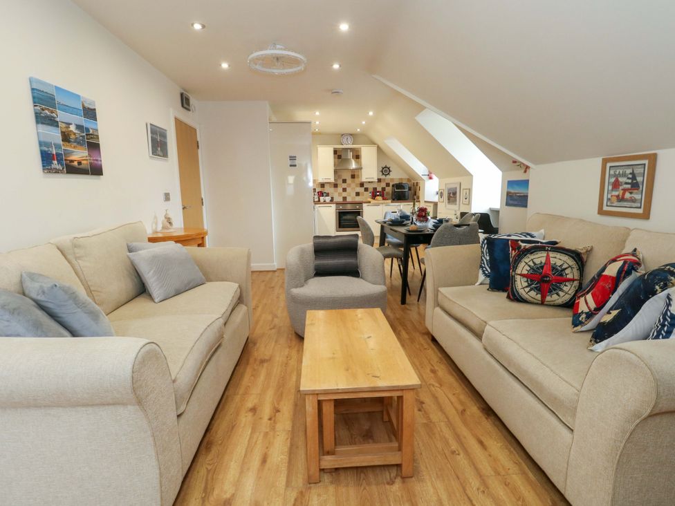 A living room with a sofa, coffee table and open kitchen at Flat 7 Weymouth