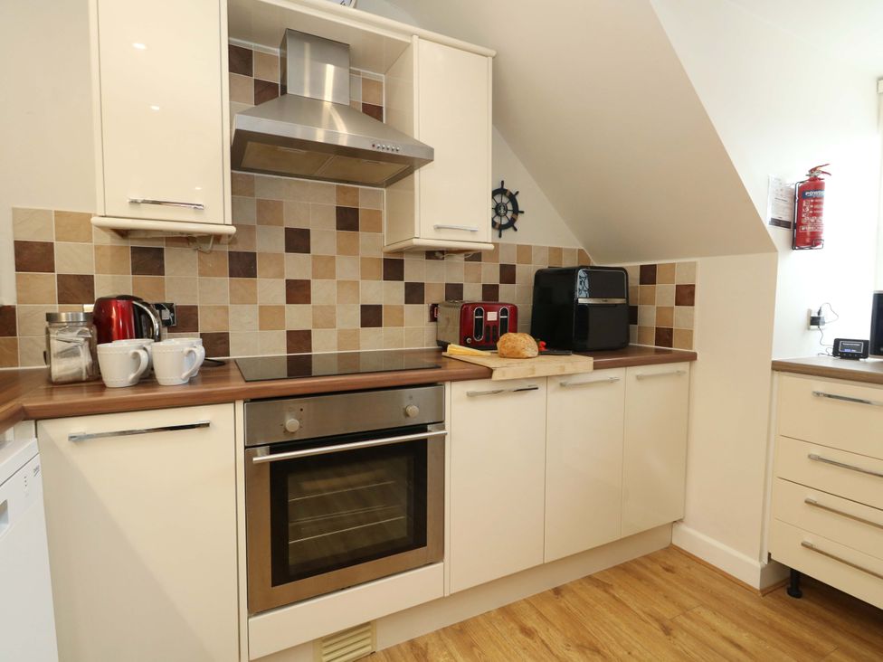 A kitchen with cabinets and appliances at Flat 7 in Weymouth
