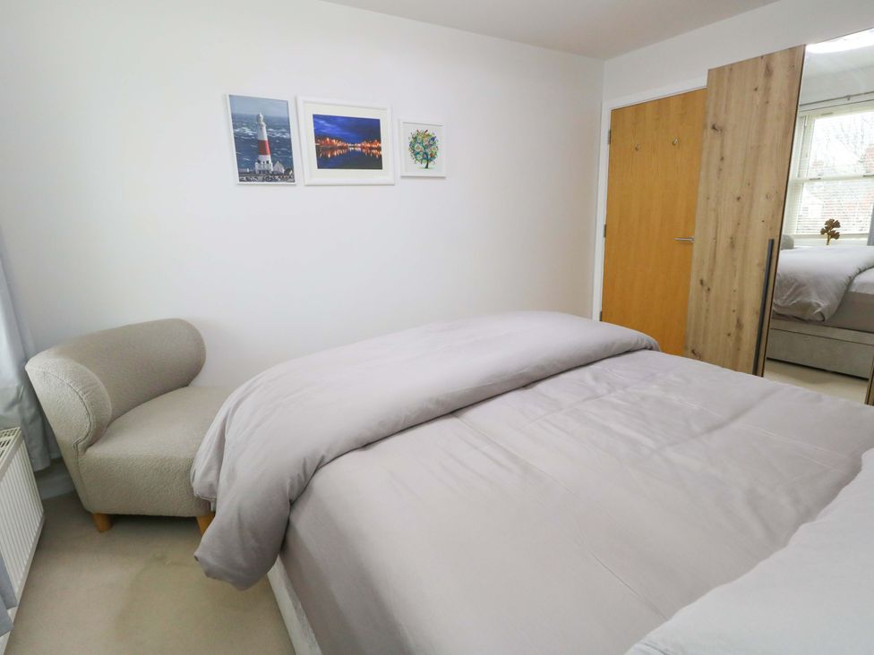 A bedroom with a bed and an armchair at Flat 7 Weymouth