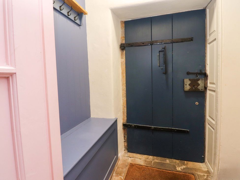 A hallway with a blue door and coat hooks at Kirk Yett in Skipton