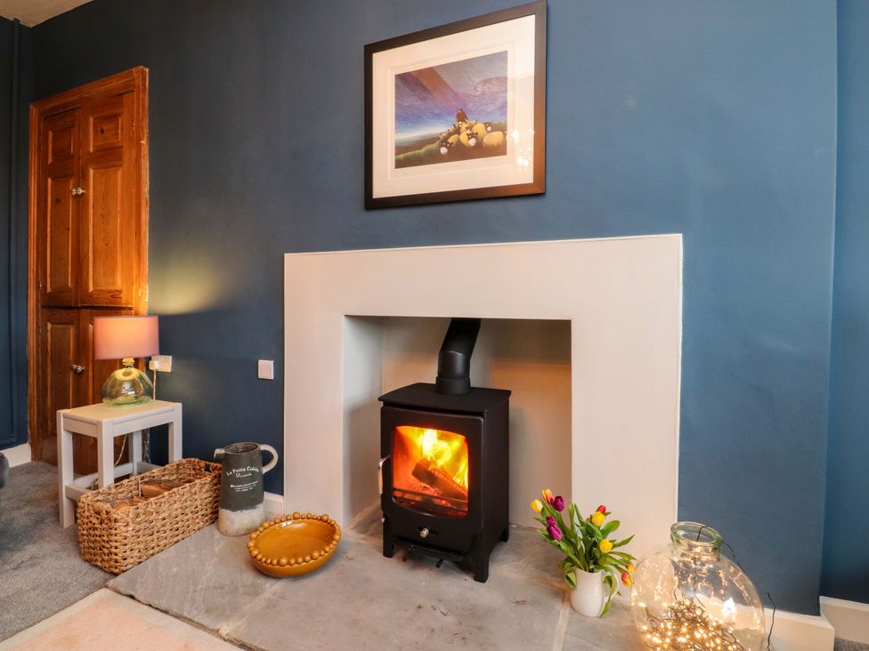 A living room with a wood stove and framed picture at Kirk Yett in Skipton
