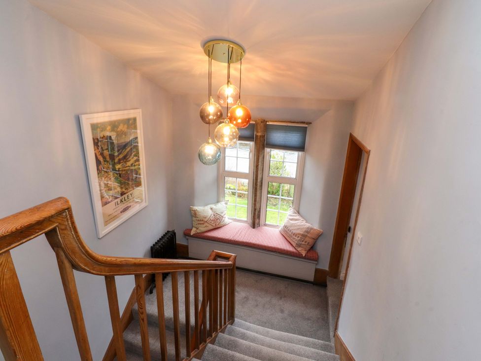 A staircase with a light fixture and a window at Kirk Yett in Skipton