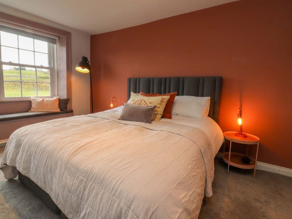 A bedroom with a bed, window seat, and lamp at Kirk Yett in Skipton