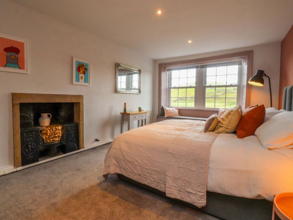 A bedroom with a bed, table, and fireplace at Kirk Yett in Skipton
