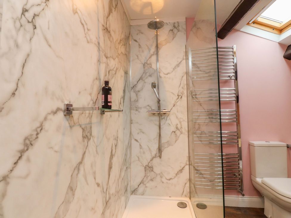 A shower with marble walls and a toilet at Kirk Yett in Skipton