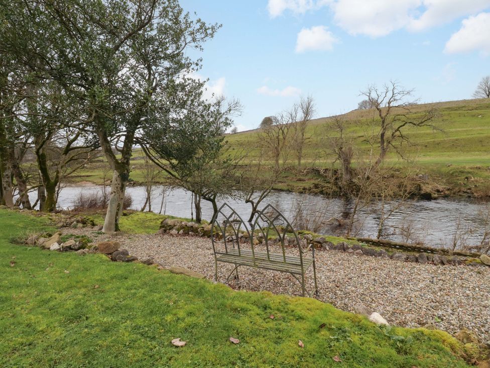 A garden with a bench beside a river at Kirk Yett in Skipton
